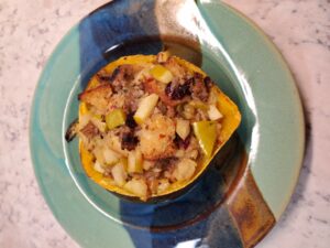 squash filled with sauase and onions on a green plate with blue and brown stripes in center